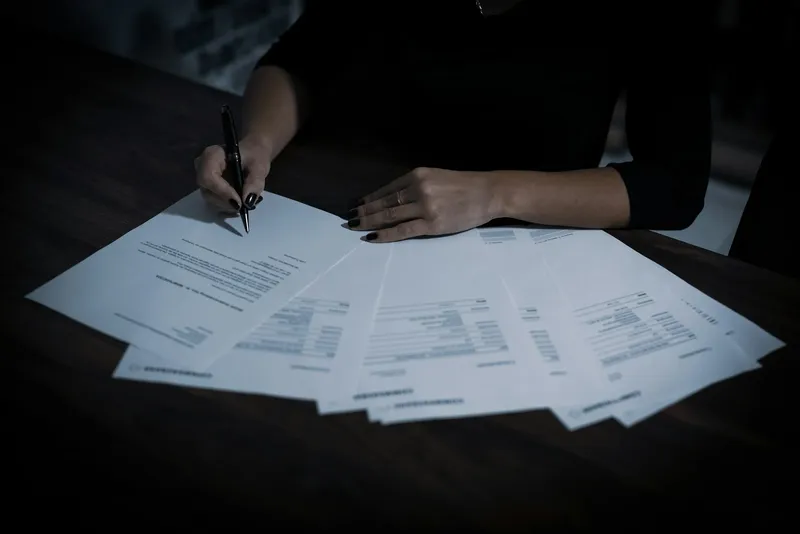 Mulher assinando um contrato com caneta sobre a mesa