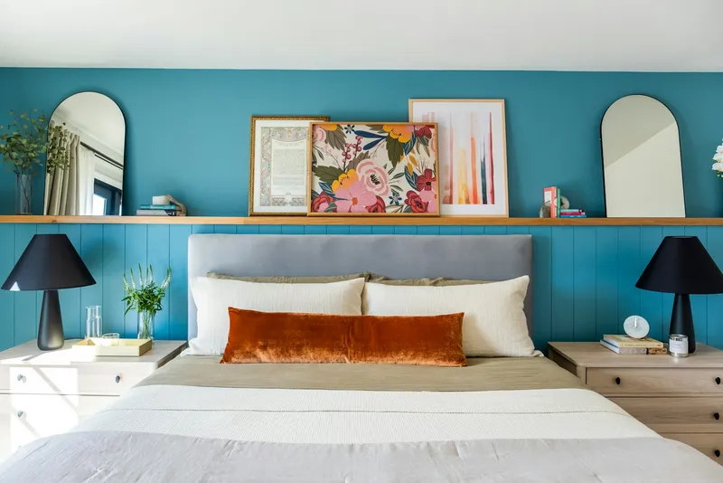 Quarto com parede azul, cama arrumada e luz natural entrando pela janela