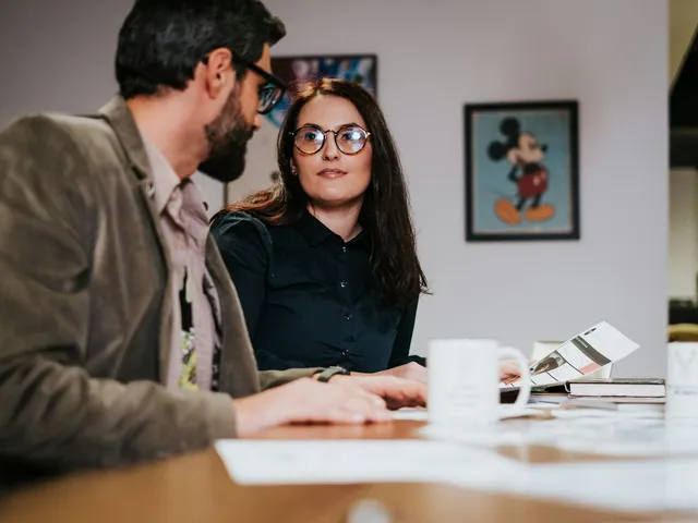 Duas pessoas sentadas à mesa organizando contas e documentos